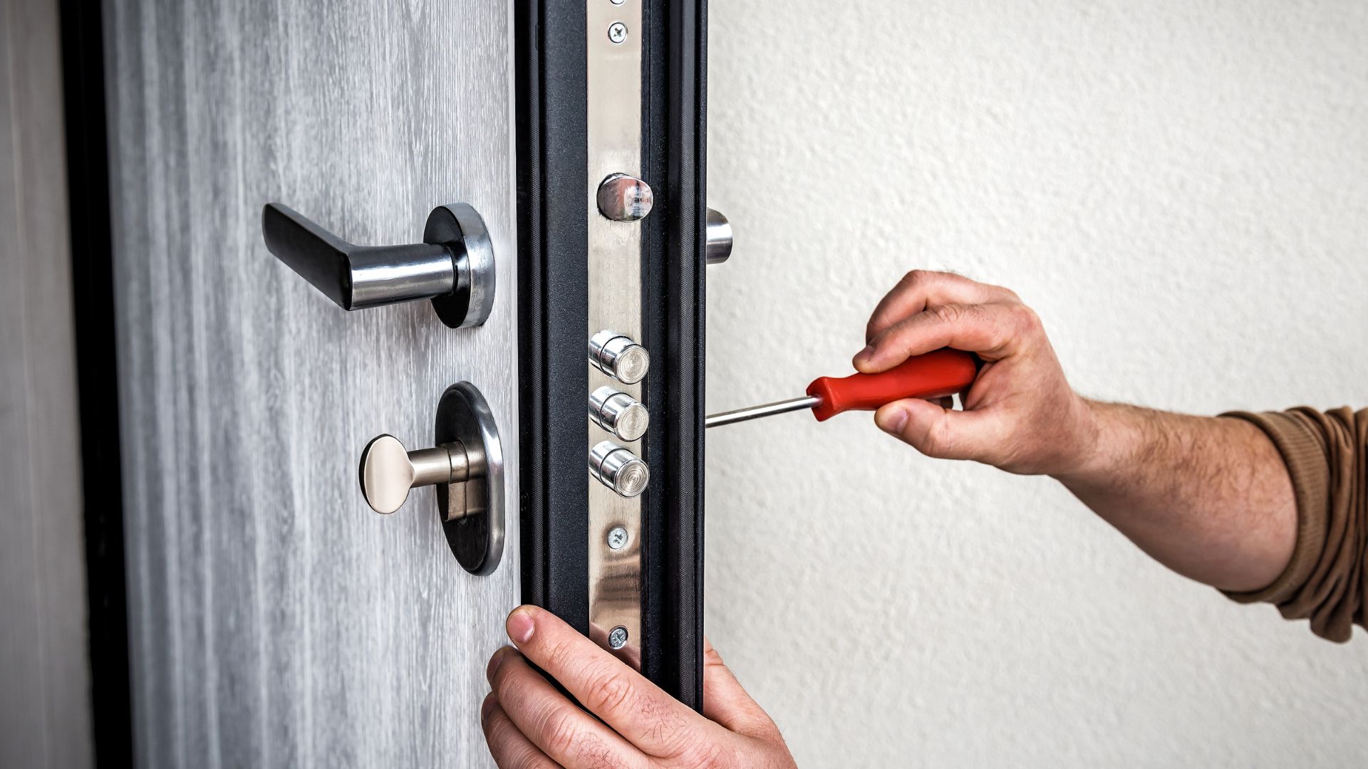 Emergency locksmith services in Houston, Texas. A professional locksmith is repairing a door lock during a home lockout situation, using a screwdriver to fix the lock mechanism. Quick, reliable locksmith solutions for home security in Houston.